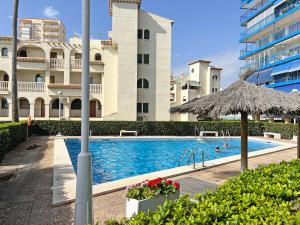 a swimming pool with an umbrella and a building at Playa y montaña. 1ª linea. Piscina. Parking . A/C in El Campello