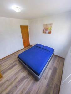Cama azul en habitación con suelo de madera en Apartamento frente a la playa de la guaira, en San Julián