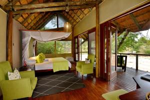a bedroom with a bed and chairs in a room at Rhino Post Safari Lodge in Skukuza +51 photos