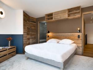 a bedroom with a large bed with a wooden headboard at Duplex plein sud à Courchevel Village - 4 pers - Pieds des pistes, balcons, parking, casier à skis - FR-1-631-73 in Courchevel