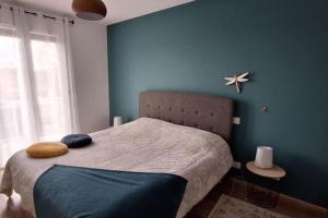 une chambre avec un lit avec un mur bleu dans l'établissement Charmante maison de ville climatisée avec Wifi, à Saint-Yrieix-la-Perche