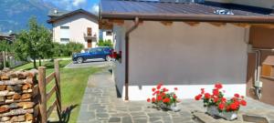 una casa con un garage bianco con fiori rossi di Maison Cocò ad Aosta