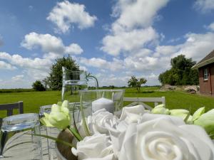 a table with white roses and a vase on it at FeWo Metje - Horumersiel in Wangerland