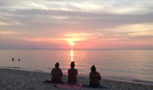 a group of people sitting on the beach watching the sunset at Jasmine & Tea House in Mae Nam