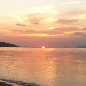 a sunset over the water with the sun in the sky at Jasmine & Tea House in Mae Nam