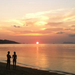 two people standing on the beach watching the sunset at Jasmine & Tea House in Mae Nam