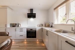 a kitchen with white cabinets and a sink at Upper Oak House in Windermere
