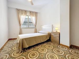 アルメリアにあるApartamento 4 dormitorios Parking incluidoのベッドと窓とラグのある寝室