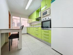 アルメリアにあるApartamento 4 dormitorios Parking incluidoのキッチン(緑のキャビネット、テーブル、電子レンジ付)