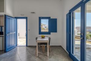 a dining room with blue doors and a table at Sunrise in Livadakia