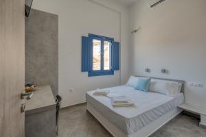 a white bedroom with a bed and a window at Sunrise in Livadakia