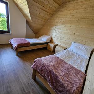 two beds in a room with a wooden wall at Przystań nad Sanem z widokiem na góry i rzekę in Tyrawa Solna +188 photos