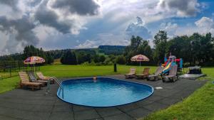 a swimming pool with chairs and a playground at Domki - Noclegi Pod Ostrym Działem in Ustrzyki Dolne