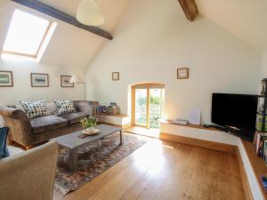 Una sala de estar con un sofá y un televisor. en Foxholes Barn, en Kidderminster