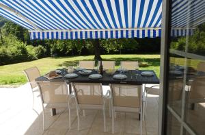 a dining table with chairs and a blue umbrella at La closerie de l'Andelle in Elbeuf-sur-Andelle
