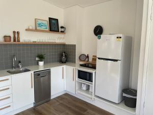 a kitchen with white cabinets and a white refrigerator at Northglow by REthynk in Jindabyne