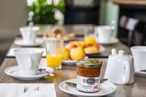 a table with cups of coffee and a jar of jam at Contact Hôtel du Champ de Mars de Saint-Brieuc in Saint-Brieuc