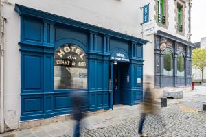 een persoon die langs een blauwe deur van een winkel loopt bij Contact Hôtel du Champ de Mars de Saint-Brieuc in Saint-Brieuc