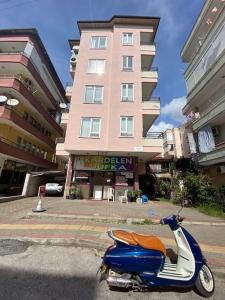 ein Roller, der vor einem hohen Gebäude geparkt ist in der Unterkunft Alanya Merkezde Süit Daire in Alanya