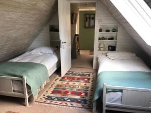 a attic bedroom with two beds and a rug at Brook Barn in Selham