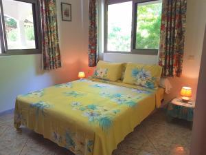 a bedroom with a yellow bed with two windows at HUAHINE - Fare Teakavehere Tipanier in Haapu