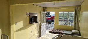 a room with a door to a balcony with a television at Loft Confortável no Centro in Chapecó
