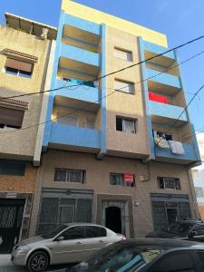 a building with balconies and cars parked in front of it at Appartement a Martil in Martil +1 photo