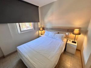 a small bedroom with a white bed and two lamps at SunAndBed ATICO FARO in Salou +27 photos