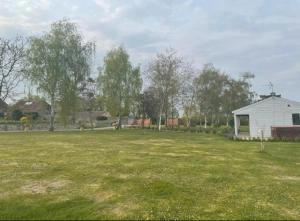 a large grass field with a white house in the background at Orchard Retreat - Rural Cabin - Private Hot Tub! in Gloucester
