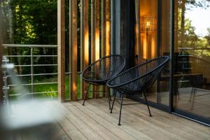 two black chairs sitting on a porch near a window at Le Nid d'Andrésis in Saint-Hilaire-les-Andrésis