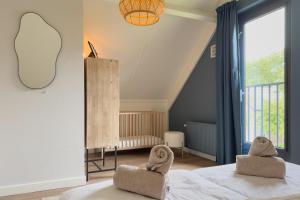 a bedroom with two chairs on a bed with a window at 6-p Wellnesshuisje met sauna/hottub bij Nijmegen in Ewijk