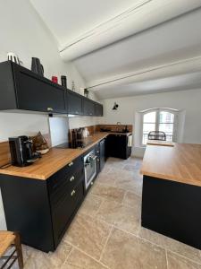 a large kitchen with black cabinets and wooden counter tops at La bohème in Lourmarin