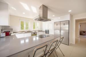 una cucina bianca con bancone e sedie di GuestReady - Sunshine oasis with pool ad Azeitao