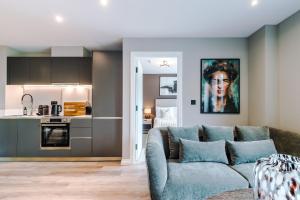 a living room with a blue couch and a kitchen at Stylish Leeds City Centre Flat - Free Parking in Leeds