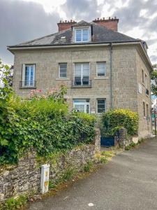 ein altes Backsteinhaus mit einer Hecke davor in der Unterkunft Appartement 2 moderne - centre in Alençon