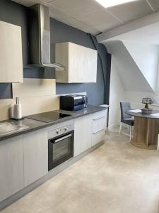 eine Küche mit einem Herd und einem Tisch darin in der Unterkunft Appartement 2 moderne - centre in Alençon