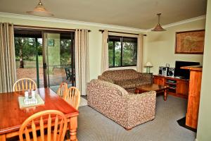 - un salon avec un canapé et une table dans l'établissement Twin Trees Country Cottages, à Pokolbin