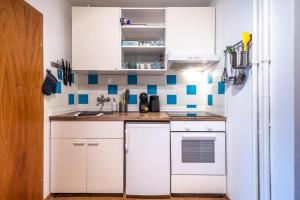 a small kitchen with white cabinets and blue tiles at MOOKI Beach Apartment in Bodensdorf