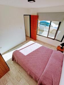 Un dormitorio con una cama y una ventana grande. en Malula Departamentos., en Playas Doradas
