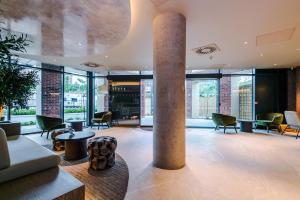 a lobby with a column and chairs and tables at Stylish Leeds City Centre Flat - Free Parking in Leeds