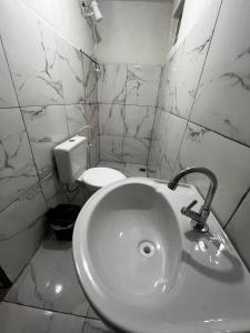 a white bathroom with a sink and a toilet at Casa Ana Brutomesso 1 in Londrina +3 photos