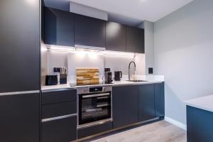 a kitchen with black cabinets and a stove at Premium 3 Bed Apartment City Centre - Free Parking in Leeds