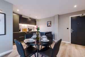a dining room with a black table and chairs at Premium 3 Bed Apartment City Centre - Free Parking in Leeds