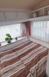 a bed in a room with two windows at übernachtung in unserem Wohnwagen in Gračac +16 photos