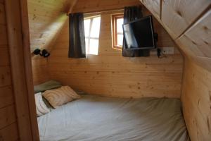 a small bedroom in a log cabin with a bed and a tv at La Cab'Armande in Libramont