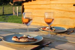 two glasses of wine and two plates of food on a wooden table at La Cab'Armande in Libramont