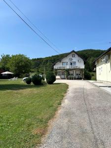 un grande edificio bianco con un prato davanti di Rooms Lucijana a Jezerce