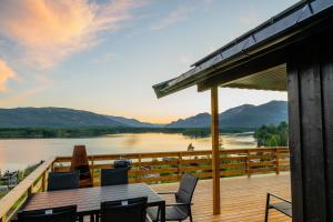 a deck with a table and chairs and a view of a river at Lakeview II Vrådal Hyttegrend in Vradal