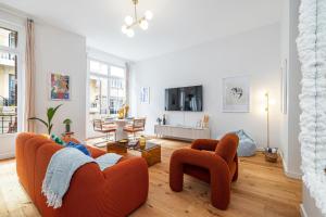 a living room with an orange couch and chairs at Soleil de la Buffa - Un joyau central à 3 min des plages in Nice