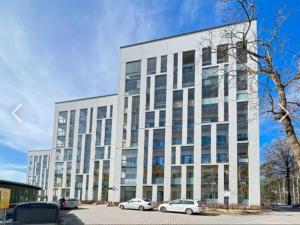 a large white building with cars parked in front of it at C&C Studio - Comfy Nest Near Airport & City Access in Vantaa